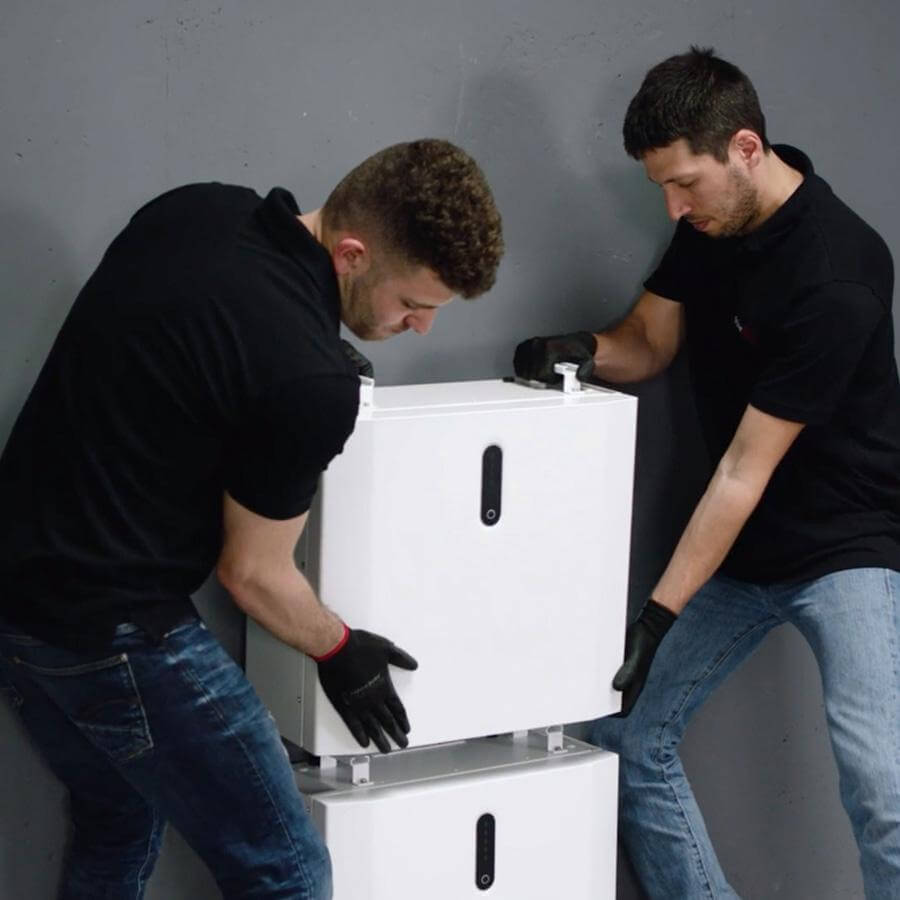 Twee monteurs stapelen een extra batterijmodule op een bestaand systeem